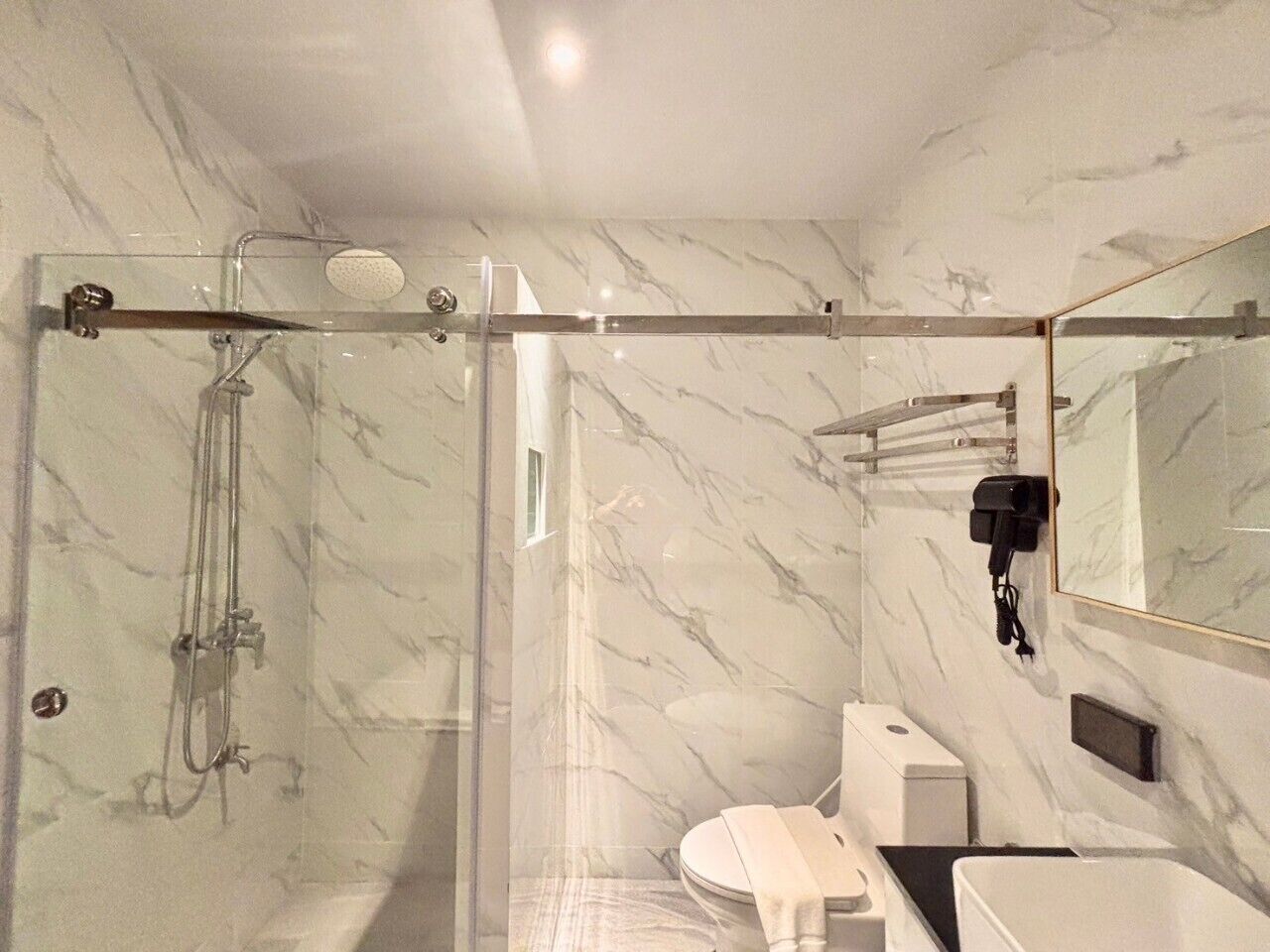 A modern bathroom with a glass-enclosed shower, a toilet, and a sink.
