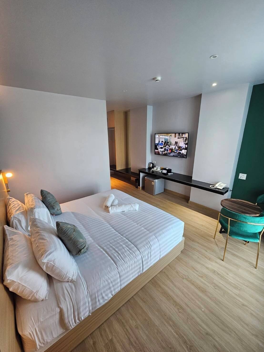 Een moderne hotelkamer met een groot bed, een bureau, een stoel en een aan de muur bevestigde televisie.