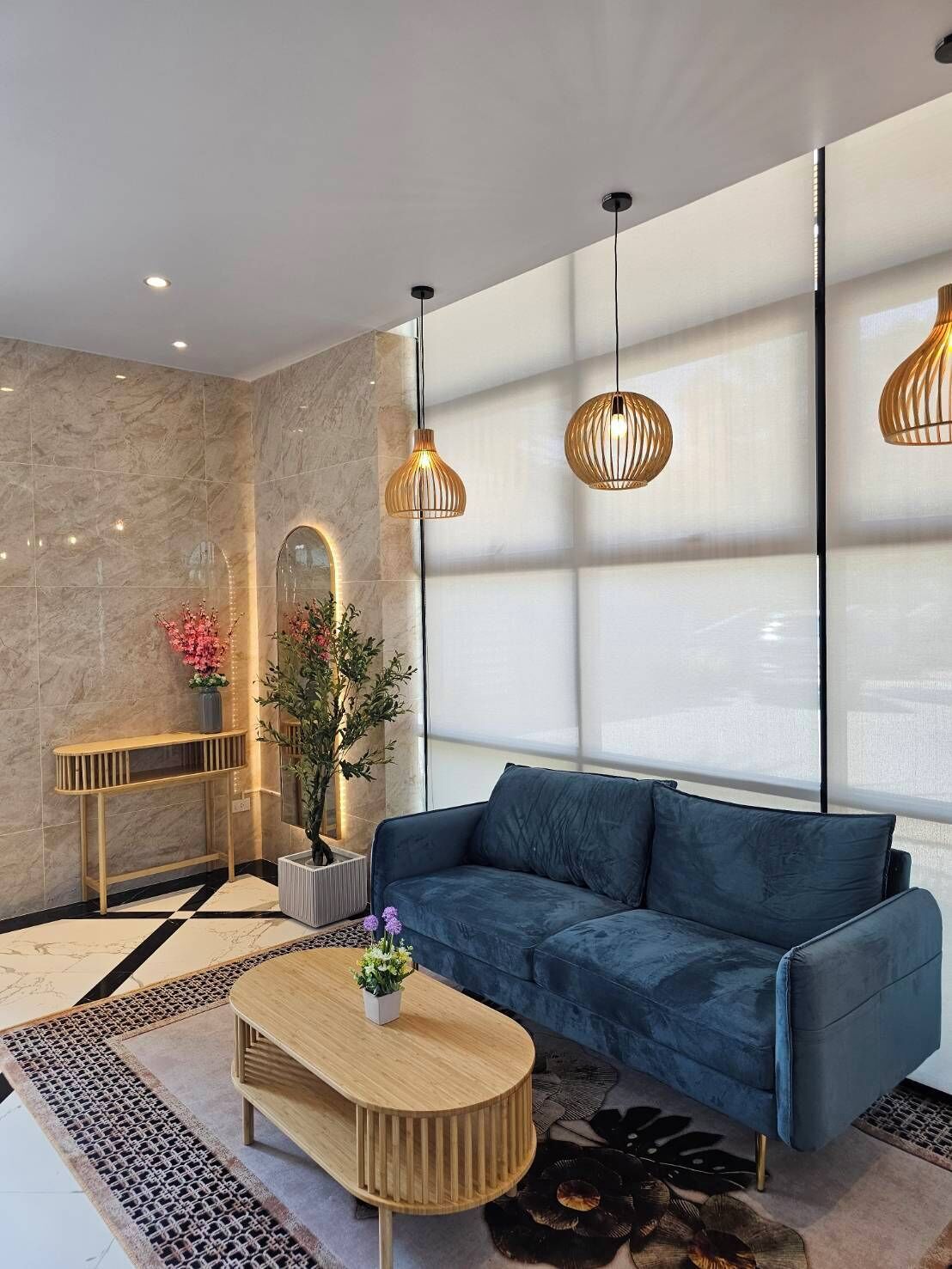 Un salon moderne avec un canapé bleu, une table basse en bois et des luminaires suspendus.