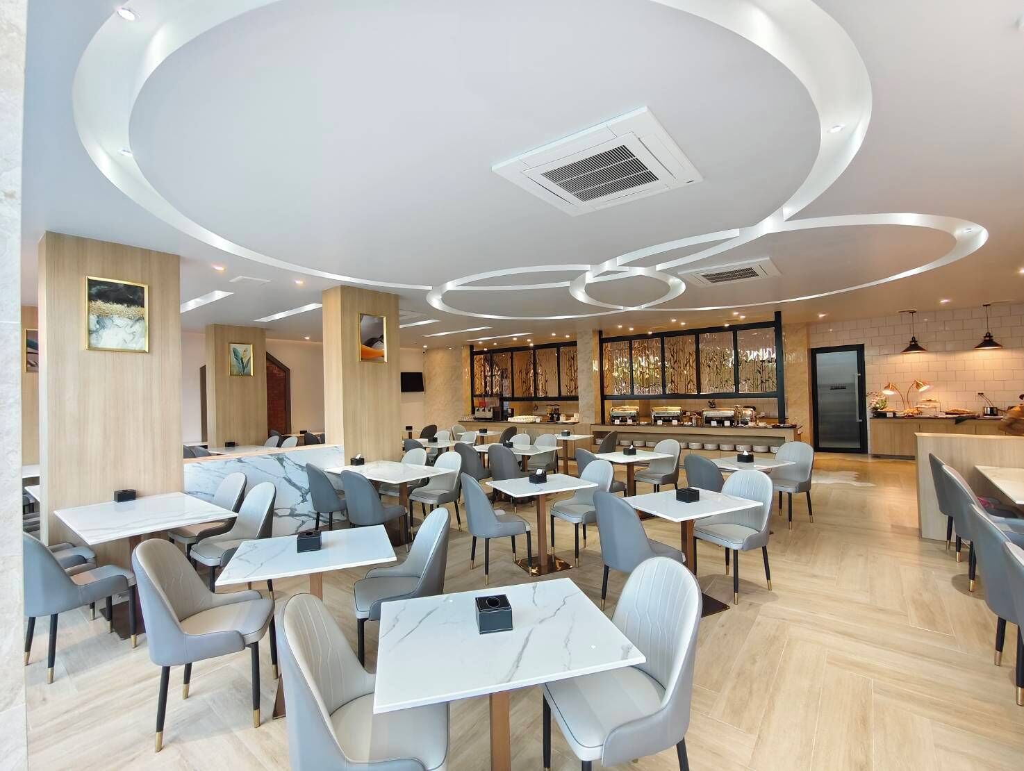 Un restaurant moderne avec des tables et des chaises rondes, un bar et un plafond décoratif.