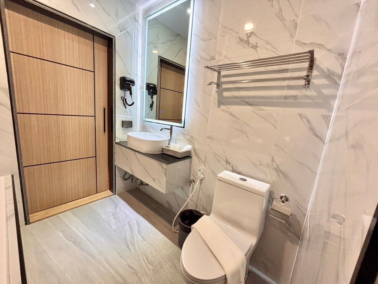 Een moderne badkamer met een houten kledingkast, een wastafel, toilet en spiegel.