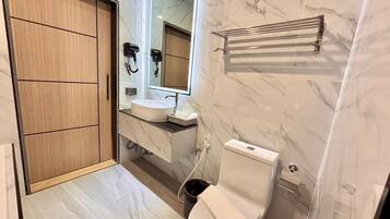 Een moderne badkamer met een houten kledingkast, een wastafel, toilet en spiegel.