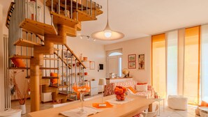 A modern kitchen with a wooden staircase, a dining table with chairs, and a view of the living area. - Vacation home Aurora by Interhome (Colico)
