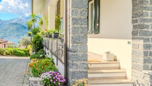 A stone building with a balcony, steps leading to a door, and a view of mountains. - Vacation home Aurora by Interhome (Colico)