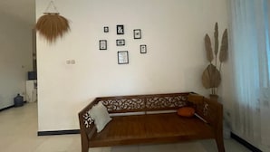 A room with a wooden sofa, a hanging decorative item, and framed pictures on the wall. - Hotel O Bogor near Taman Safari formerly Villa Ruko (Cisarua)