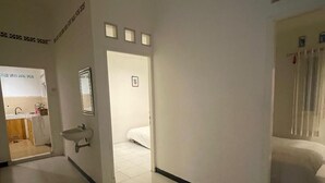 A hotel room with a bed, a sink, and a mirror. There is a door leading to another room. - Hotel O Bogor near Taman Safari formerly Villa Ruko (Cisarua)