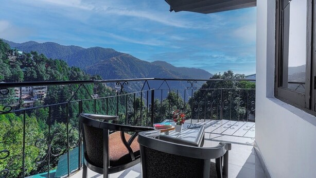 Un balcón con vista a montañas y árboles.