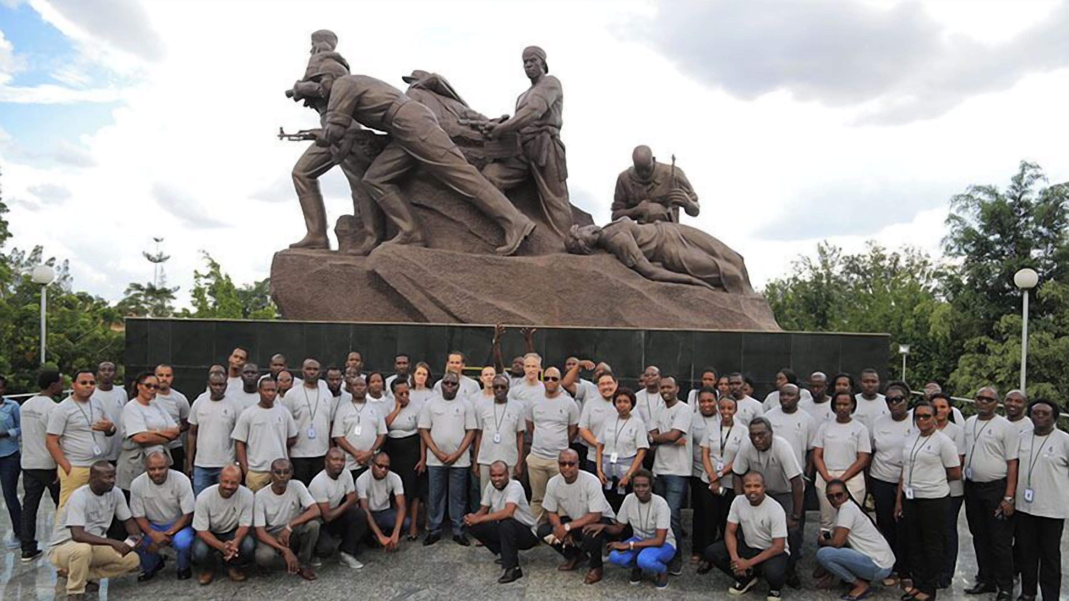 Un grupo de personas posando frente a una gran escultura al aire libre.