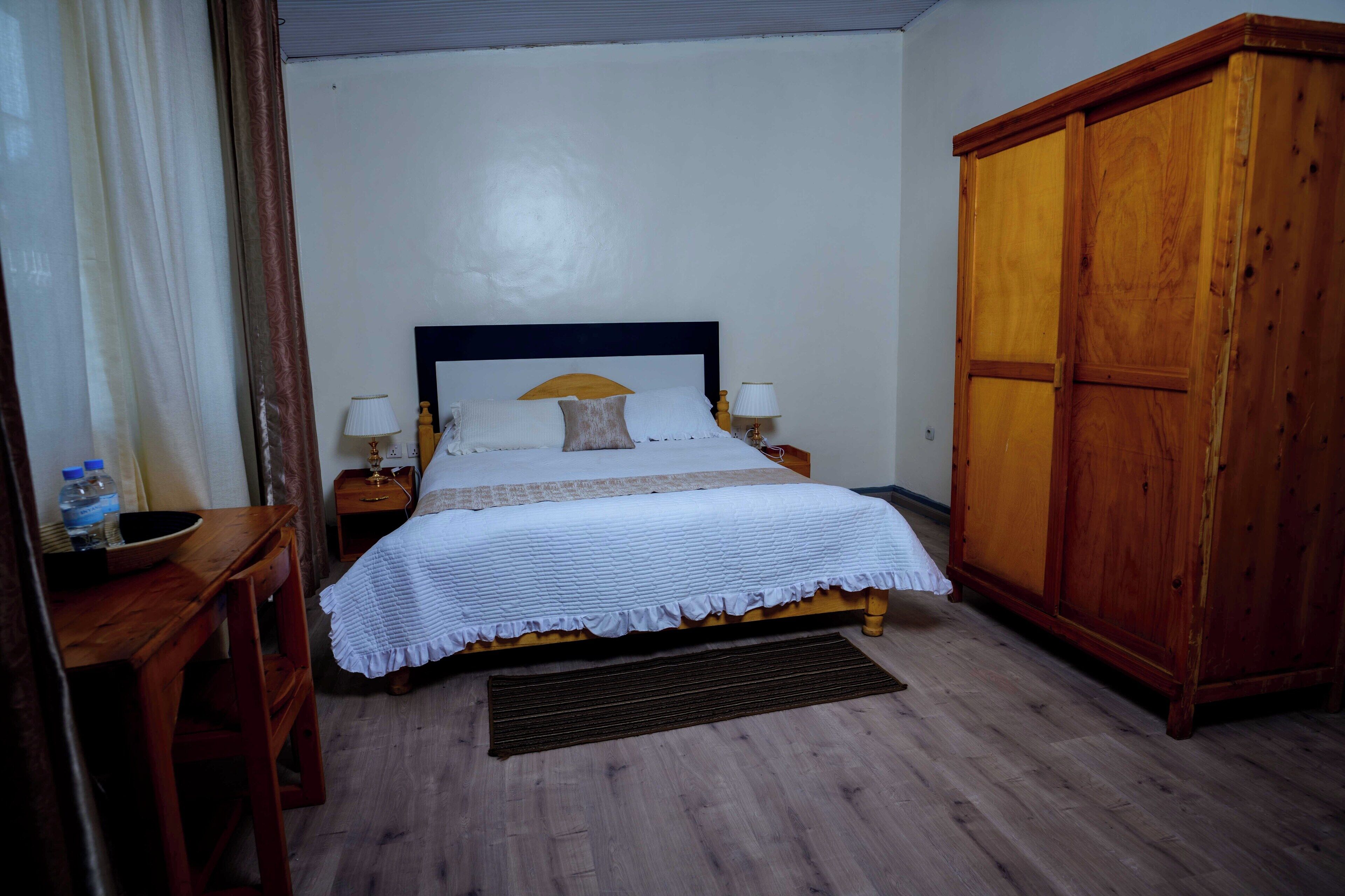 A neatly arranged bedroom with a bed, bedside tables, a wardrobe, and a desk.