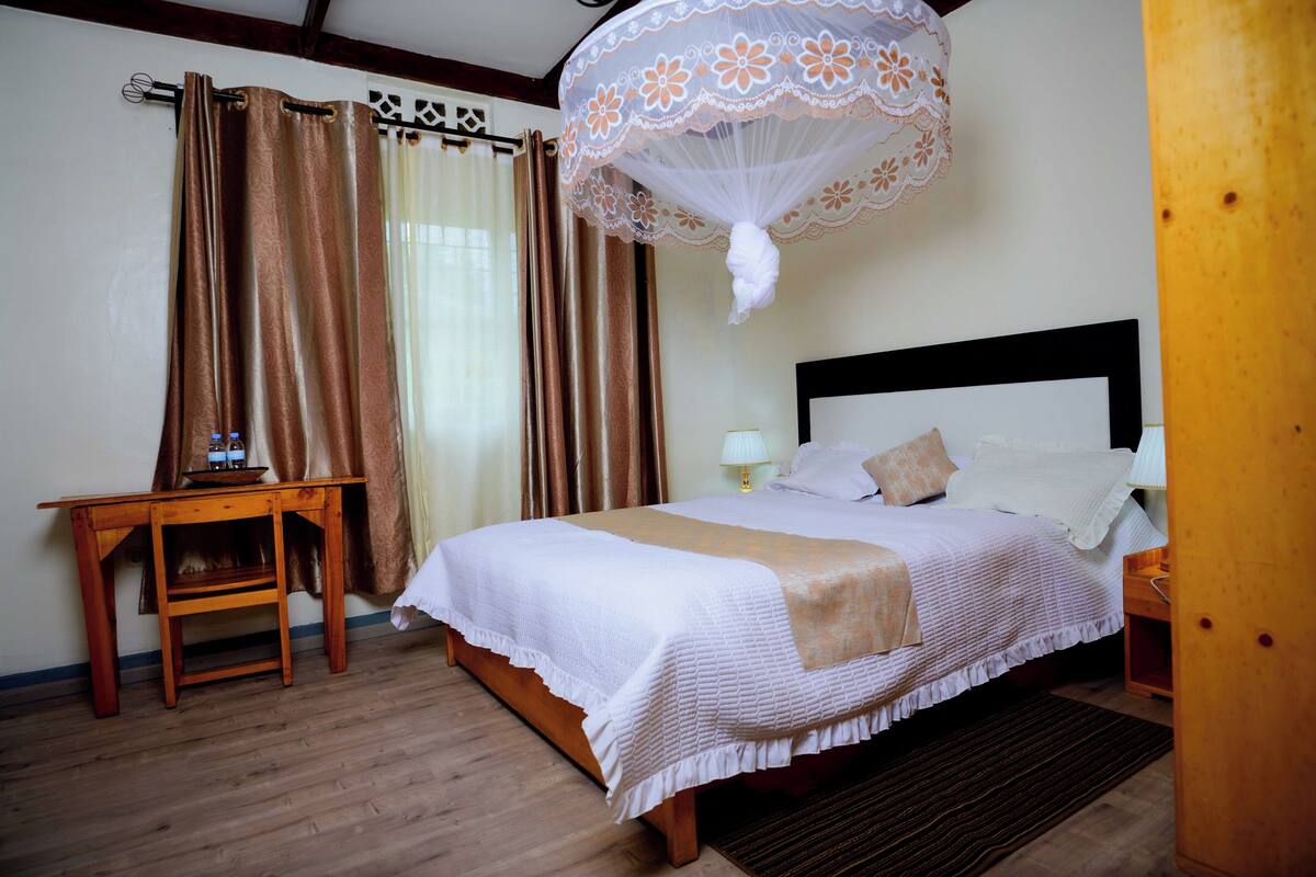 A neatly arranged bedroom with a bed, bedside table, and a hanging mosquito net.
