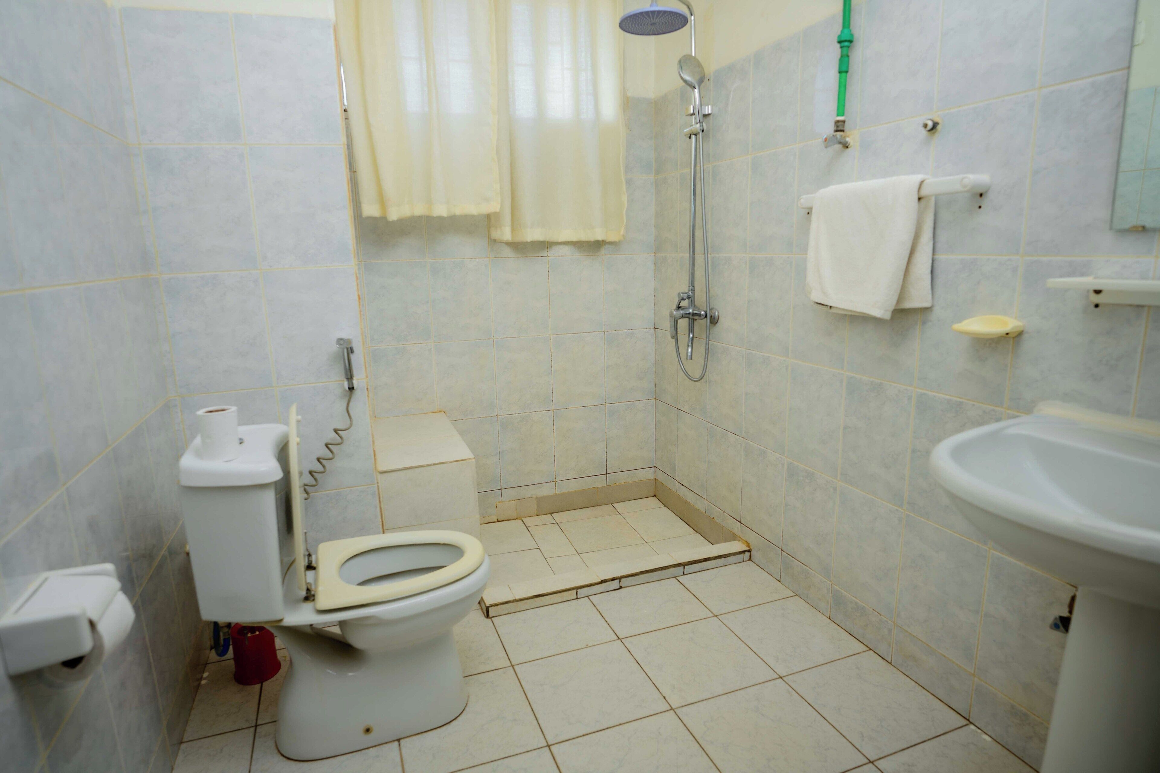 A bathroom with a toilet, shower, and sink.