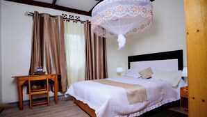 A neatly arranged bedroom with a bed, bedside table, and a hanging canopy. - Quality Inn Motel (Busasamana)
