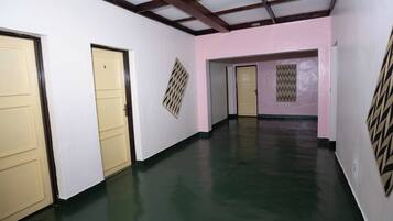 A hallway with cream-colored doors, a green floor, and a pink wall.