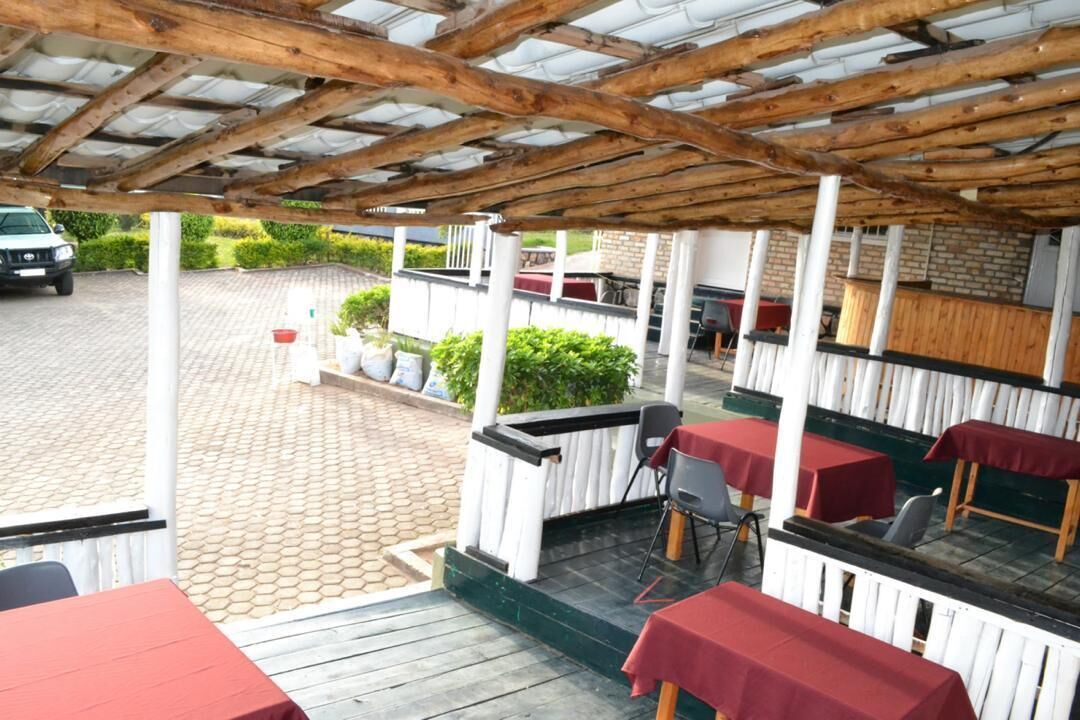 An outdoor patio area with wooden tables and chairs, covered by a wooden pergola.
