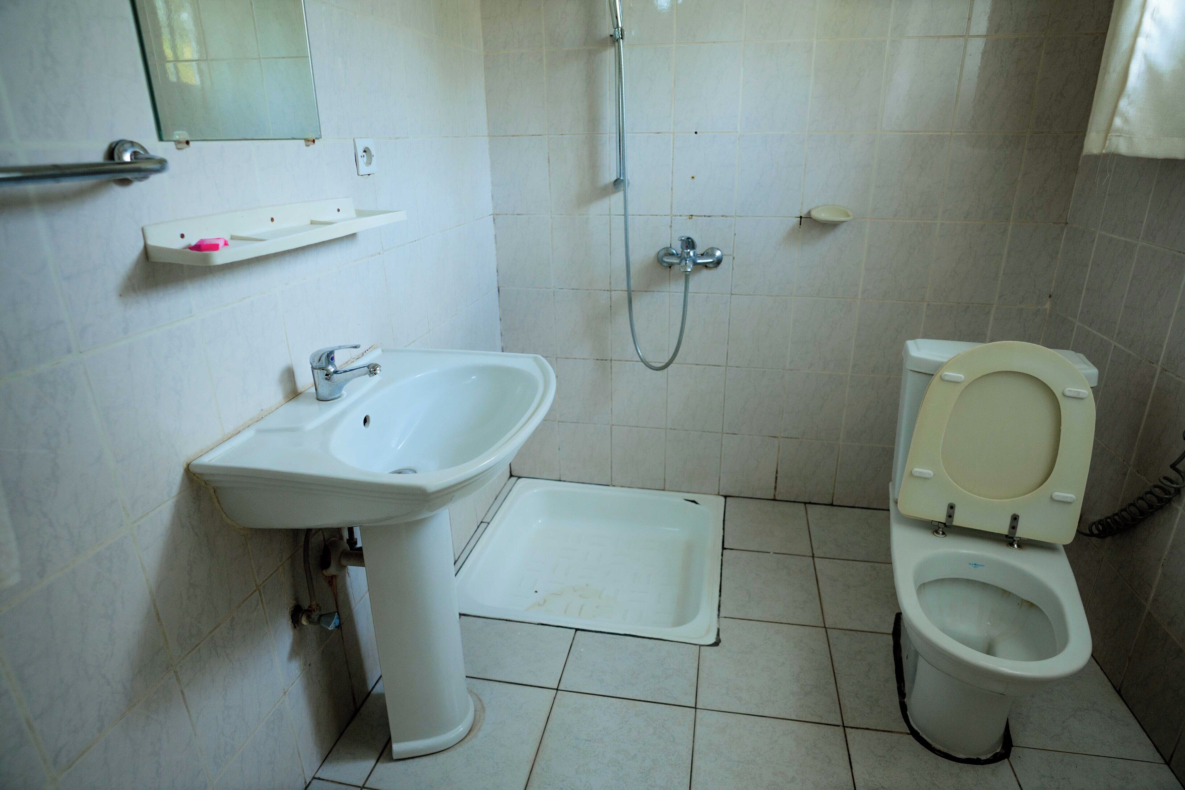 A small bathroom with a sink, toilet, and shower.