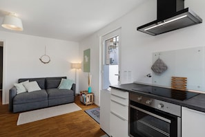 A compact kitchen with a stove, oven, and a window with blinds. - Apartment 'Marie' with Mountain View, Private Terrace and Wi-Fi (Durbach)