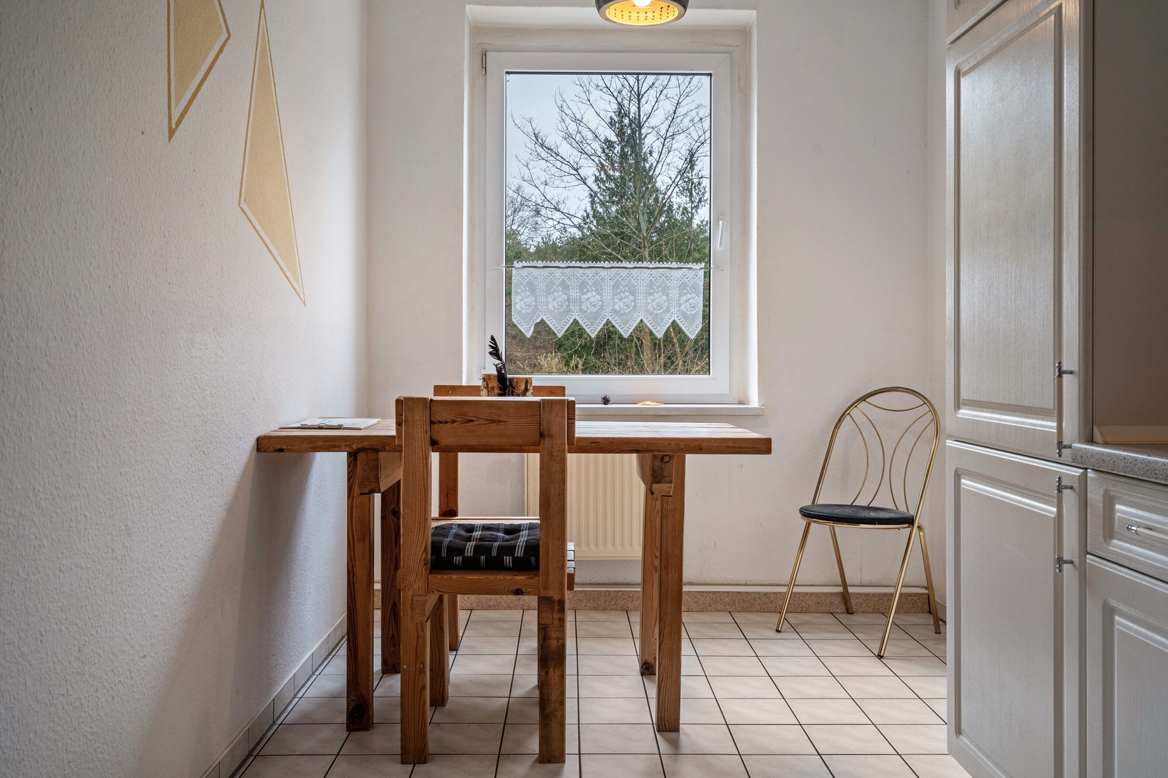 A kitchen with a window, a wooden table, a chair, and a radiator.