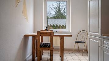A kitchen with a window, a wooden table, a chair, and a radiator.