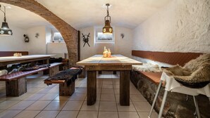 A rustic dining area with a wooden table, benches, and a stone wall. - Apartment 4 – Surrounded by Nature (Lychen)