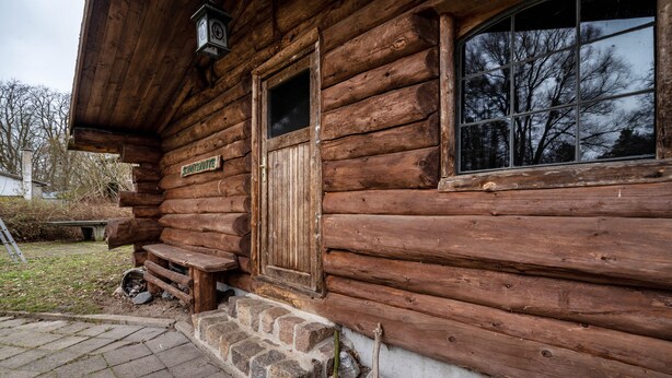 A wooden cabin with a stone foundation, a wooden door, and a window. - Apartment 4 – Surrounded by Nature (Lychen)