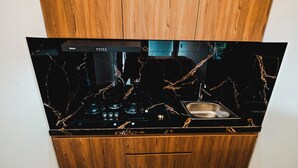 A kitchen with a black countertop, a stove, and a sink. - Queenara Local House (Carangsari)