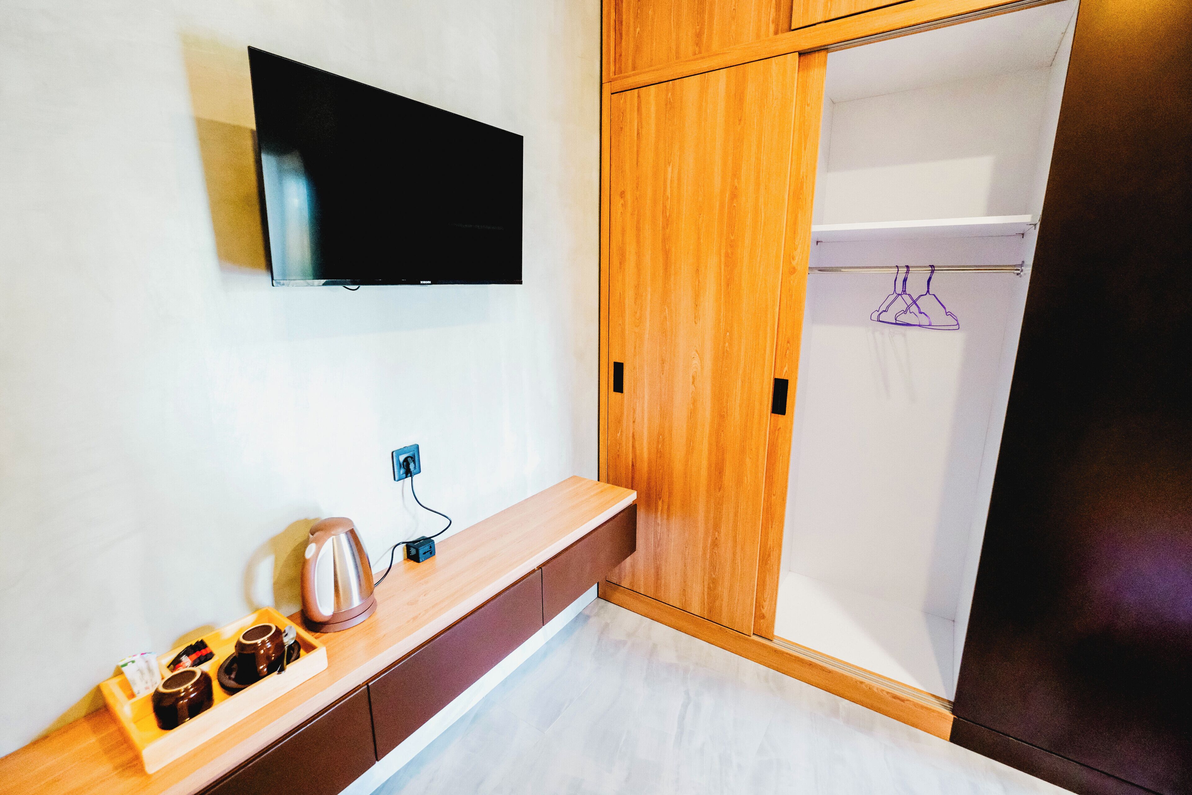 Uma casa de banho moderna com toucador de madeira, uma televisão de ecrã plano na parede e um porta-toalhas com uma toalha pendurada.