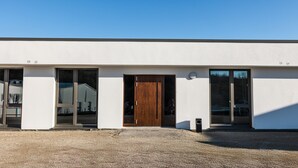 A modern building with a large wooden door, large windows, and a gravel driveway. - Room '12' with Wi-Fi (Dußlingen)