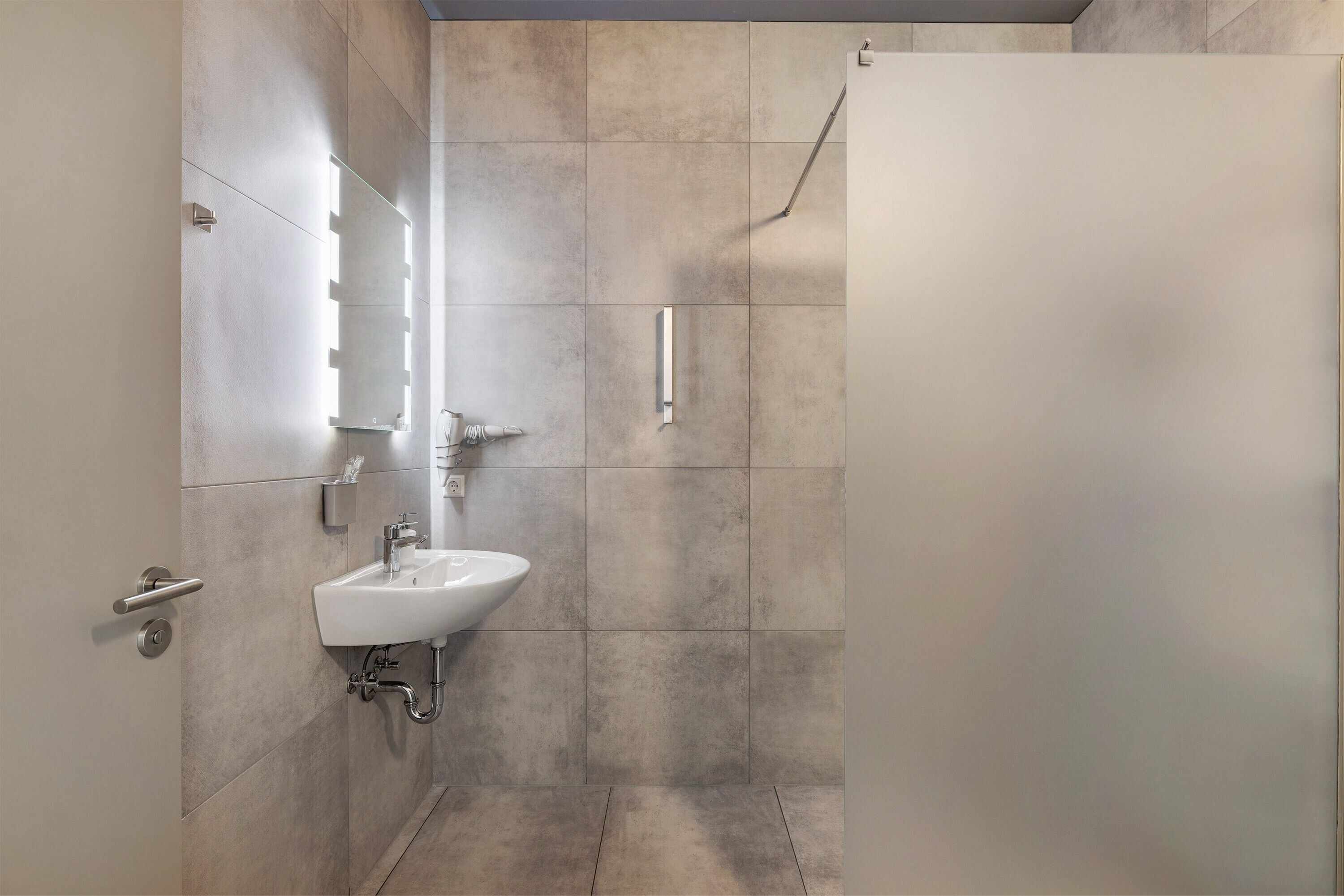 Un baño moderno con lavamanos, espejo y ducha.