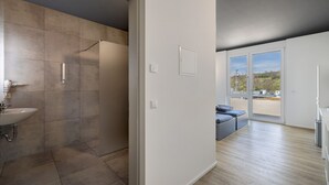 A modern bathroom with a sink and shower, a large window with a view, and a light-colored floor. - Room '12' with Wi-Fi (Dußlingen)