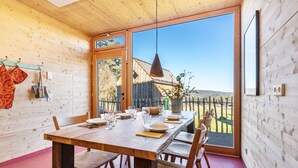 A wooden interior with a dining table set for four, a large window, and a view of the outside. - Tiny House 'Tanne' in the Heart of the Northern Black Forest (Schömberg)