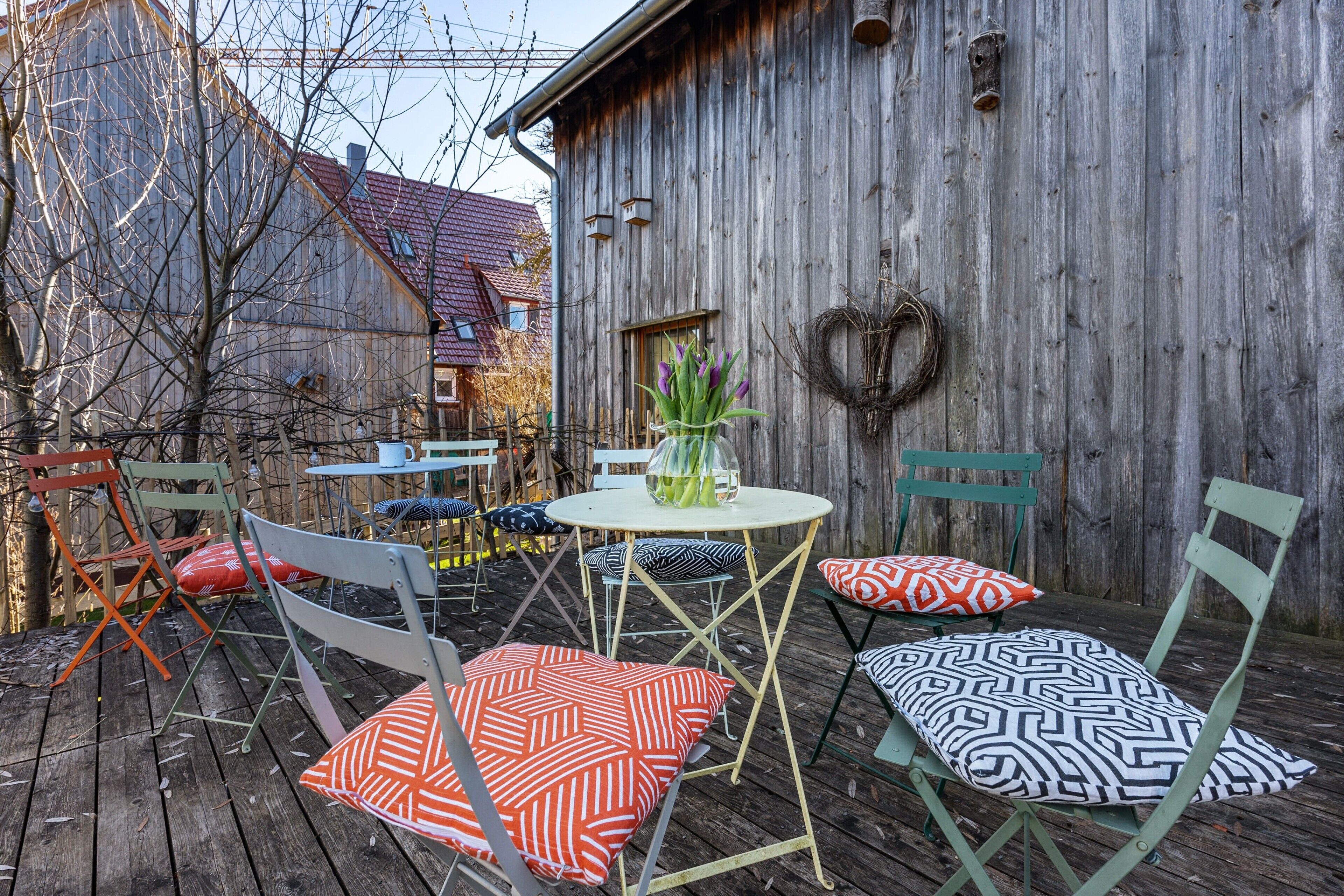 A wooden deck with outdoor furniture, a table, and a decorative wreath on the wall.