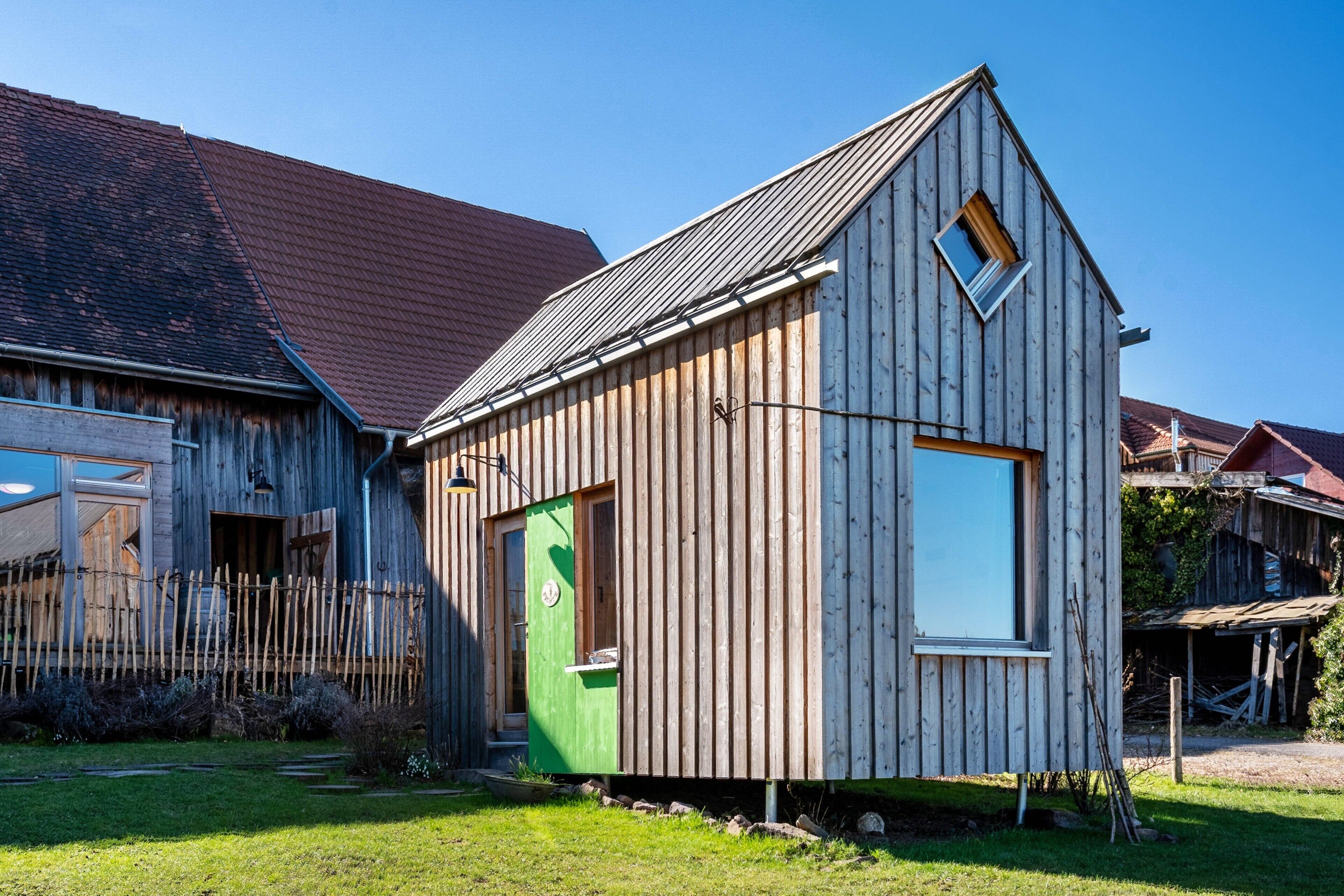 A wooden cabin with a sloped roof, a green door, and a window.