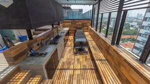 Un espacio moderno para comer al aire libre con piso de madera, parrilla metálica y asientos.