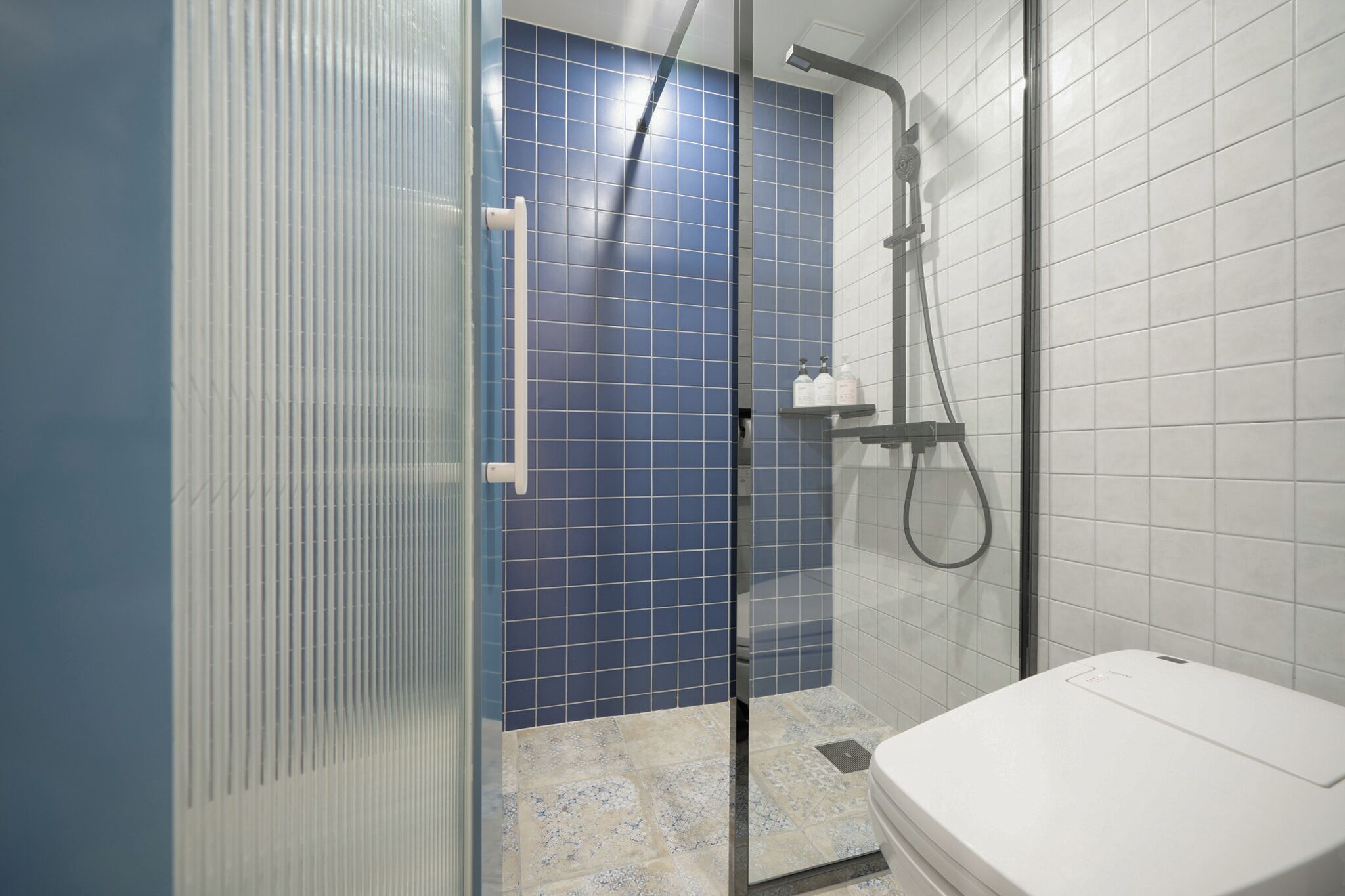A bathroom with a shower, a toilet, and a glass door.