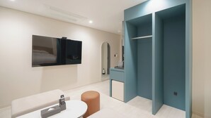 A modern hotel room with a bed, a TV, a desk, and a wardrobe.