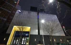 A modern building with a distinctive facade featuring a pattern of lights. - HOTEL GRAND PARIS (Gwangju)