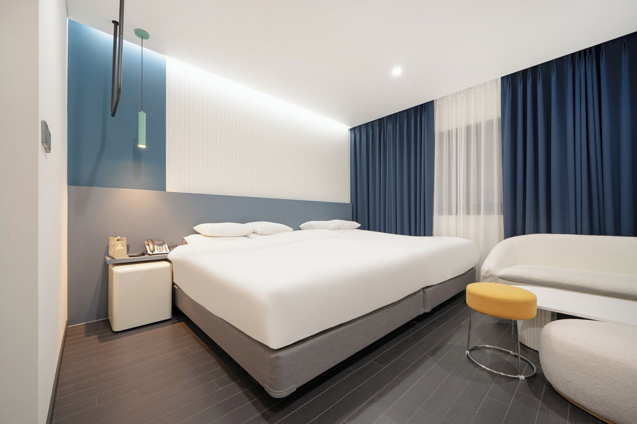 A modern hotel room with a large bed, a bedside table with a lamp, and a chair.