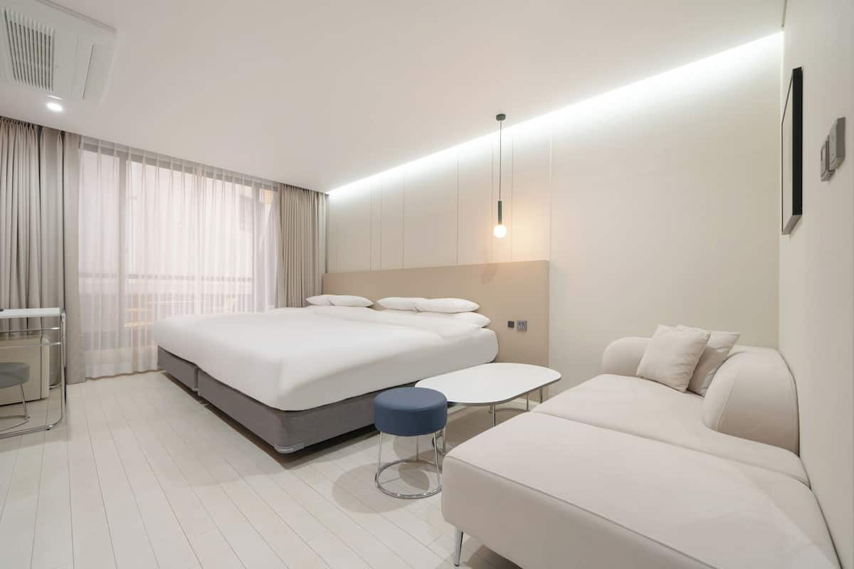 Ett modernt hotellrum med en stor säng, ett litet bord, en soffa och ett skrivbord.