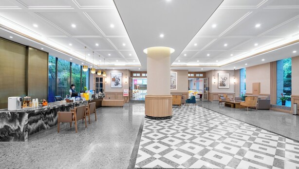 A spacious lobby with a marble reception desk, comfortable seating areas, and large windows offering views of greenery. - shuaifubosongfandian (Wuhan)