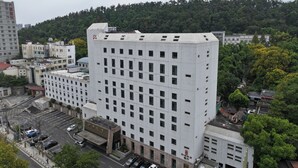 A multi-story hotel with a modern architectural design, featuring a large parking area in front. - shuaifubosongfandian (Wuhan)