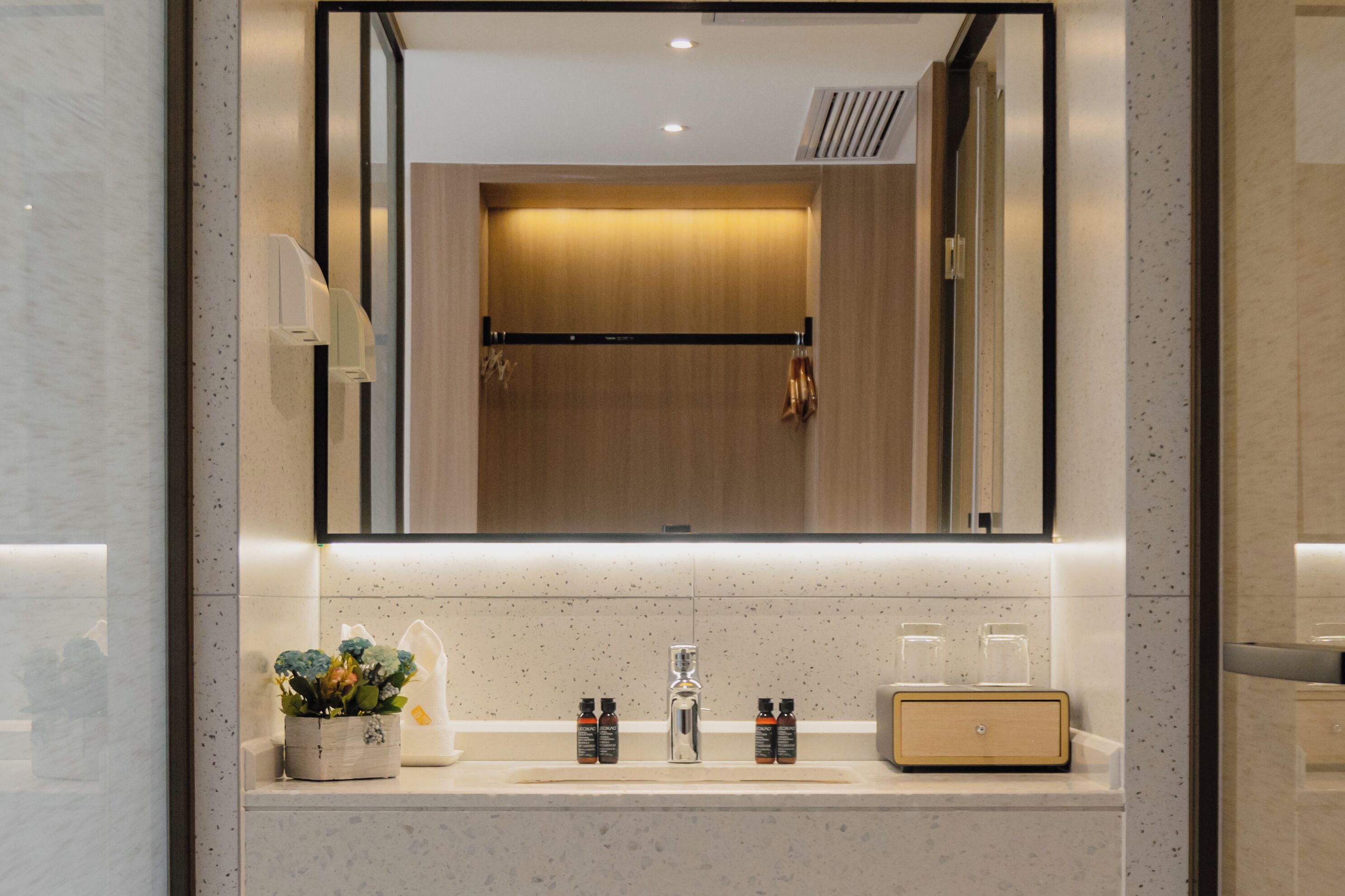 A modern bathroom with a large mirror, a sink, and a vanity area.
