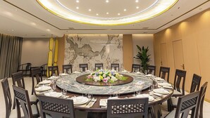 A conference room with a round table, chairs, and a central floral arrangement. - shuaifubosongfandian (Wuhan)