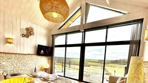 A spacious bedroom with a large window, a bed, a sofa, and a hanging light fixture. - Rèverie en Périgord du Domaine des Hauts de Rouquette (Eymet)