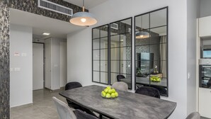 A modern dining area with a large table, chairs, and a fruit bowl.