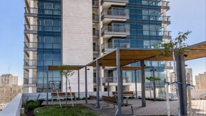 A high-rise residential building with multiple balconies and a covered outdoor area with seating.