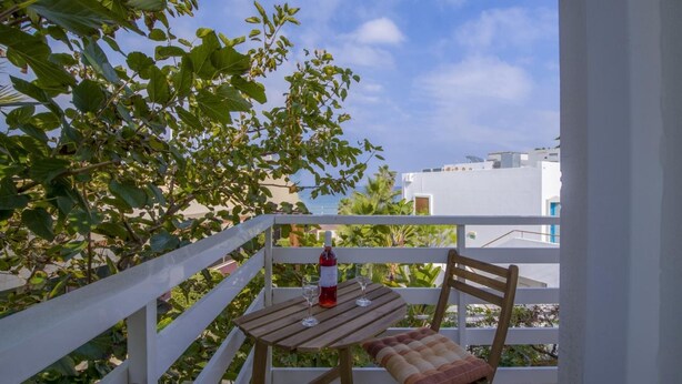 A balcony with a wooden table, a cushioned bench, and a bottle of red wine. - Alisahni Home 1, Villa (Chania)