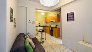 A compact living space with a kitchenette, a sofa with cushions, and a ceiling light fixture. - Alisahni Home 1, Villa (Chania)