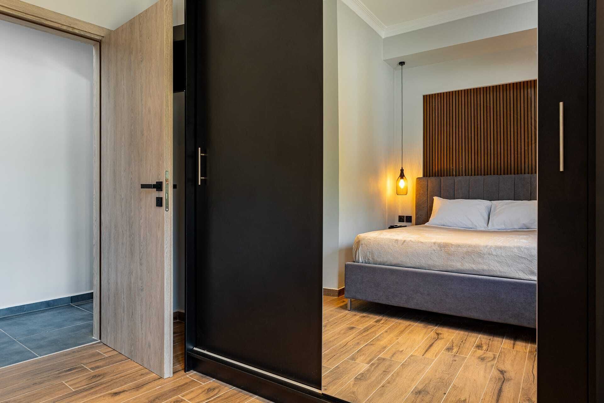 A modern bedroom with a bed, a wooden wardrobe, and a nightstand.