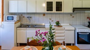 A compact kitchen with white cabinets, a microwave, a sink, and a stove. - Nonna Lena by Interhome (Molini di Prelà)