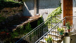 A stone house with a wooden door, a window with metal bars, and a staircase with metal railings. - Nonna Lena by Interhome (Molini di Prelà)